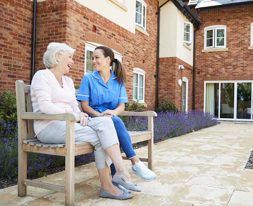 A caregiver and an older adult reviewing a care plan together at the kitchen table.